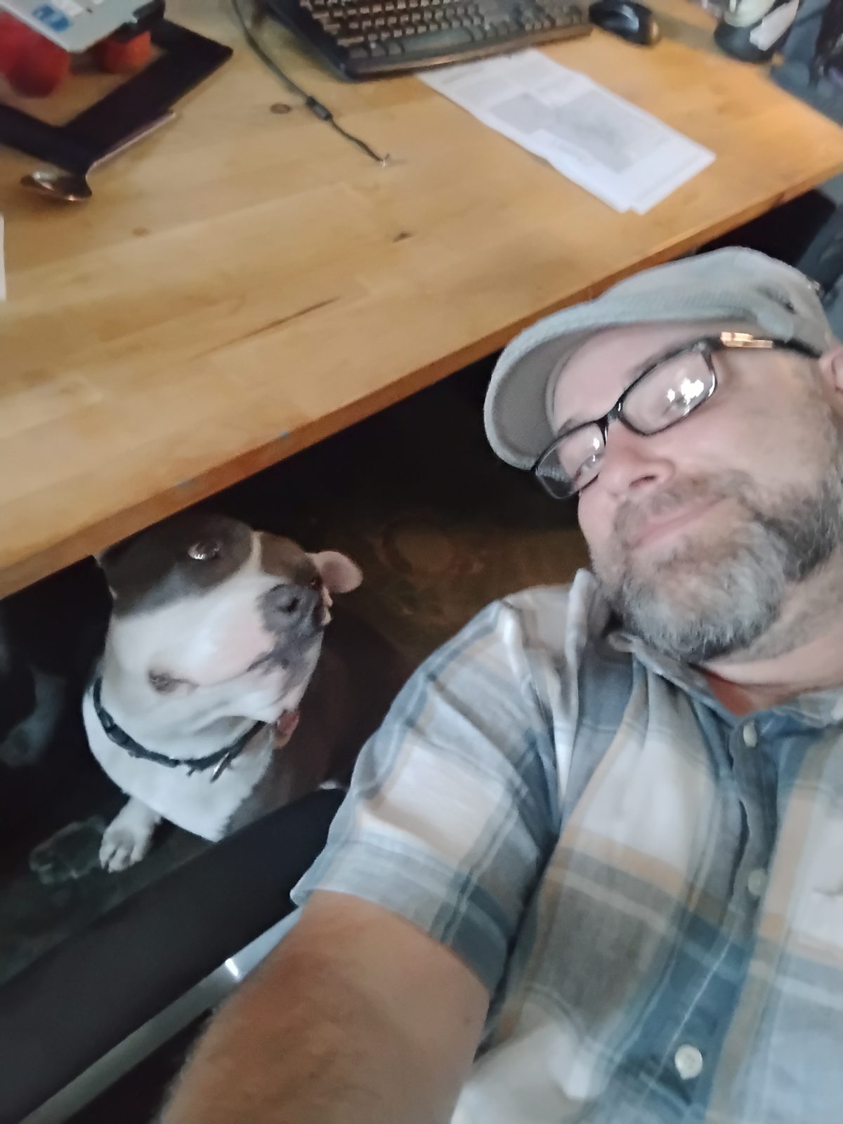 Deven smiling in a selfie with Unity looking up at him from under his desk, home again.